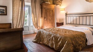 Een slaapkamer met een bed, een houten garderobe en een stenen muur.