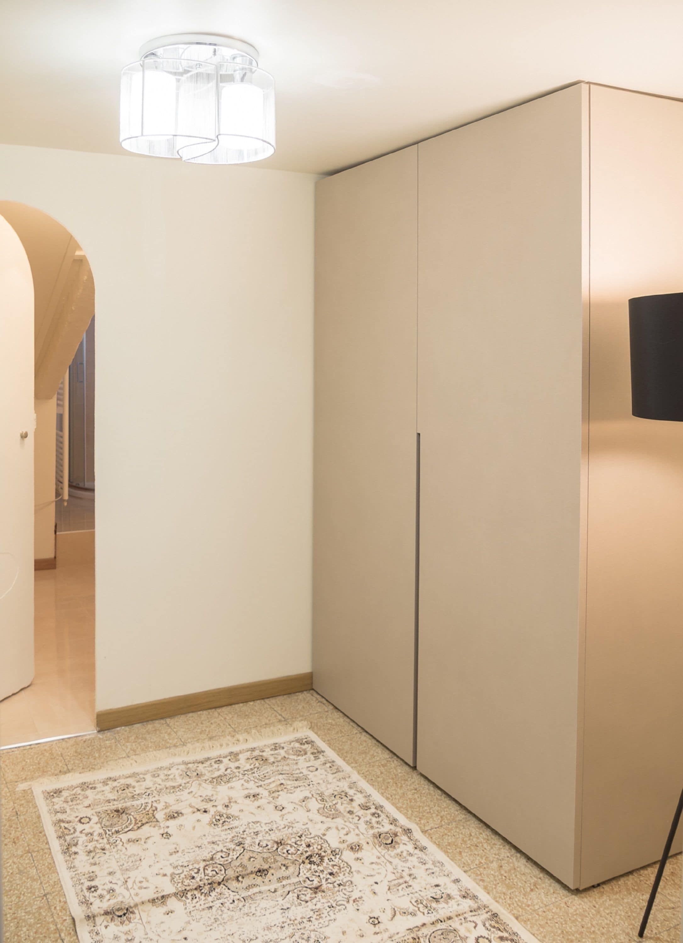 A room with a large wardrobe, a patterned rug, and a ceiling light fixture.