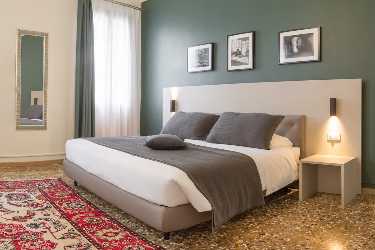 Ein modernes Schlafzimmer mit einem großen Bett, einem roten und beigefarbenen Teppich und drei gerahmten Bildern an der Wand.