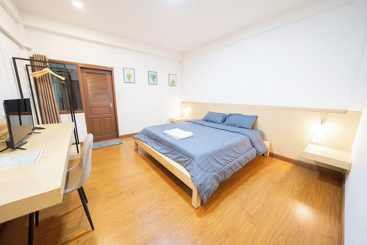 A bedroom with a bed, bedside tables, a desk, and a chair.