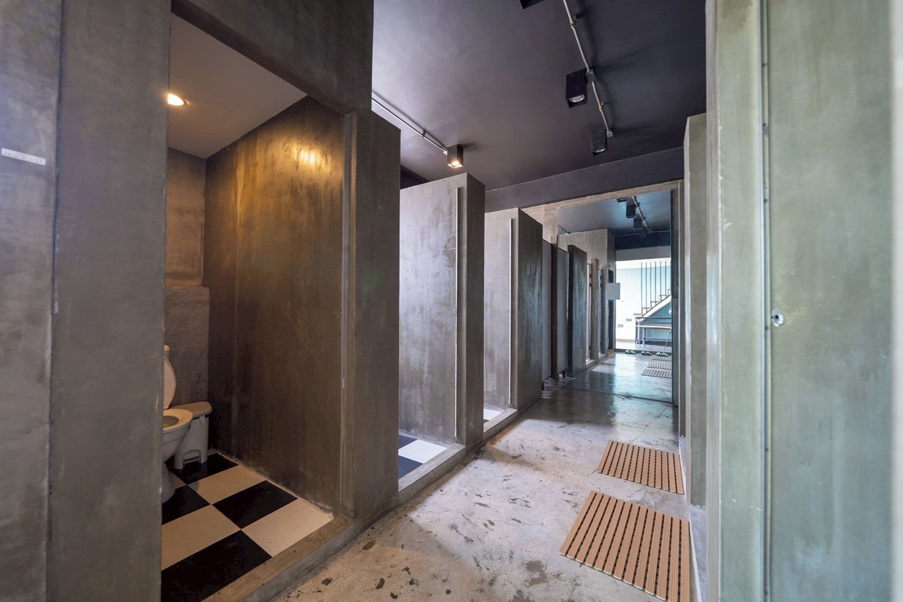 A hallway with a checkered floor, a toilet, and concrete walls.
