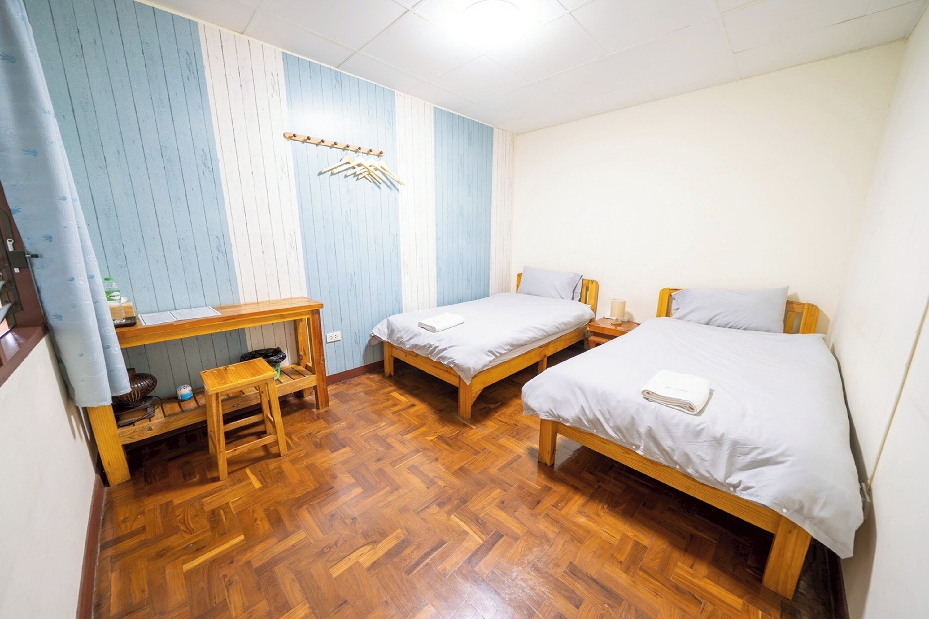 Ein Zimmer mit zwei Holzbetten, einem kleinen Schreibtisch und einem Stuhl.