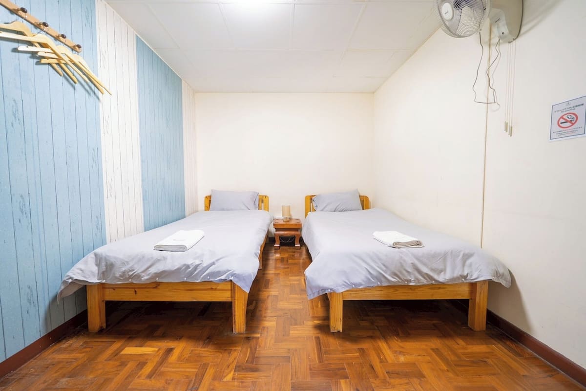 A room with two wooden beds, a wooden floor, and a blue wall.