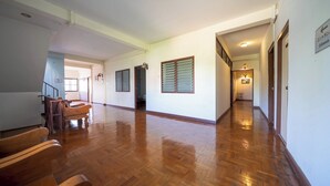 Un pasillo amplio con suelo de madera, una escalera y una puerta que da a una habitación.