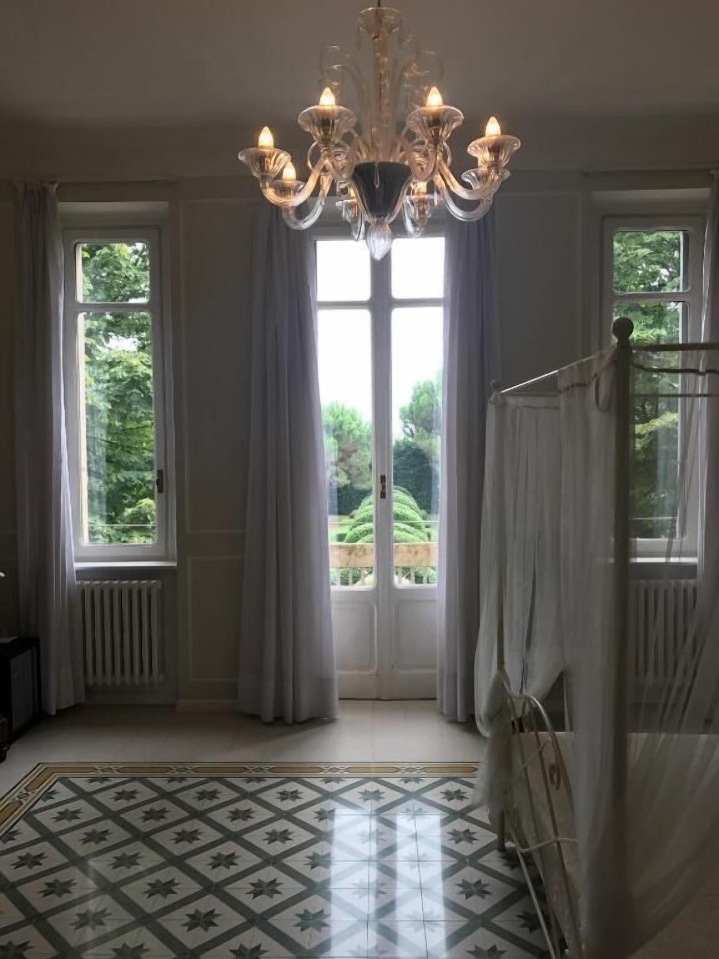 Una habitación con candelabro, ventanas amplias y suelo estampado.