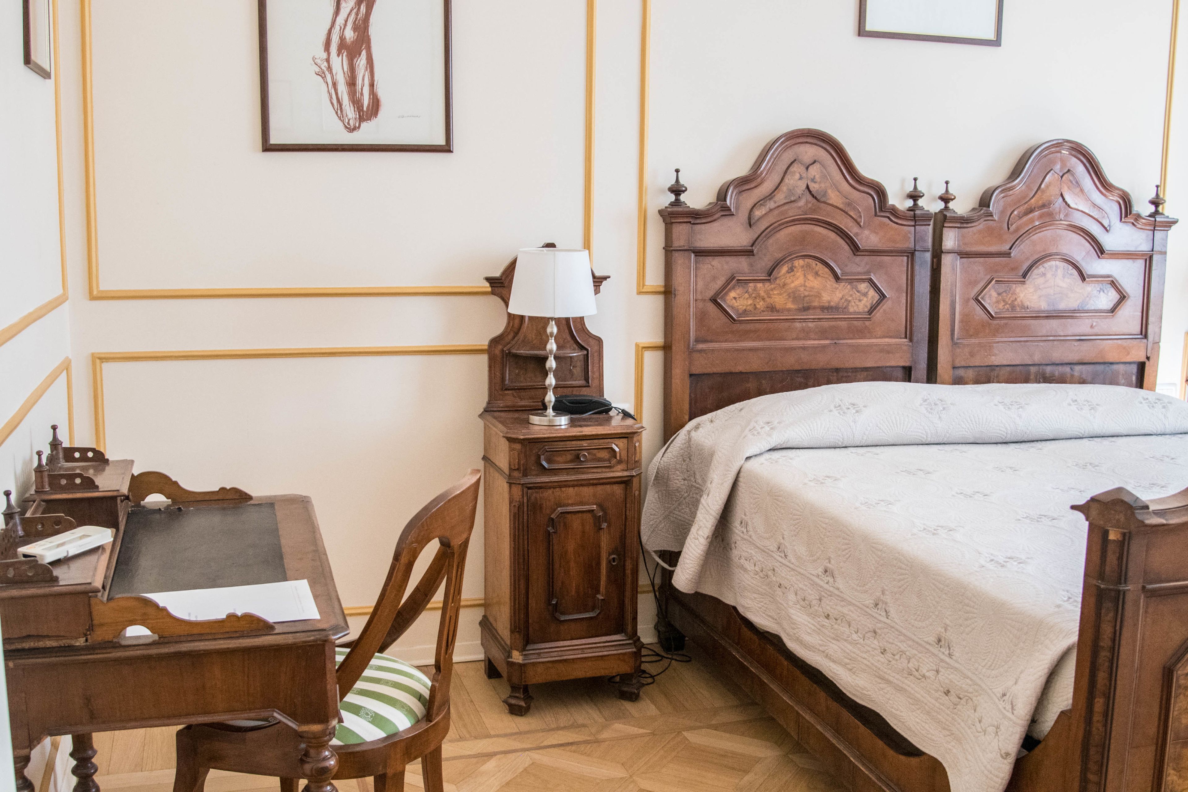 Une chambre avec un lit en bois, un bureau avec une lampe et une chaise.