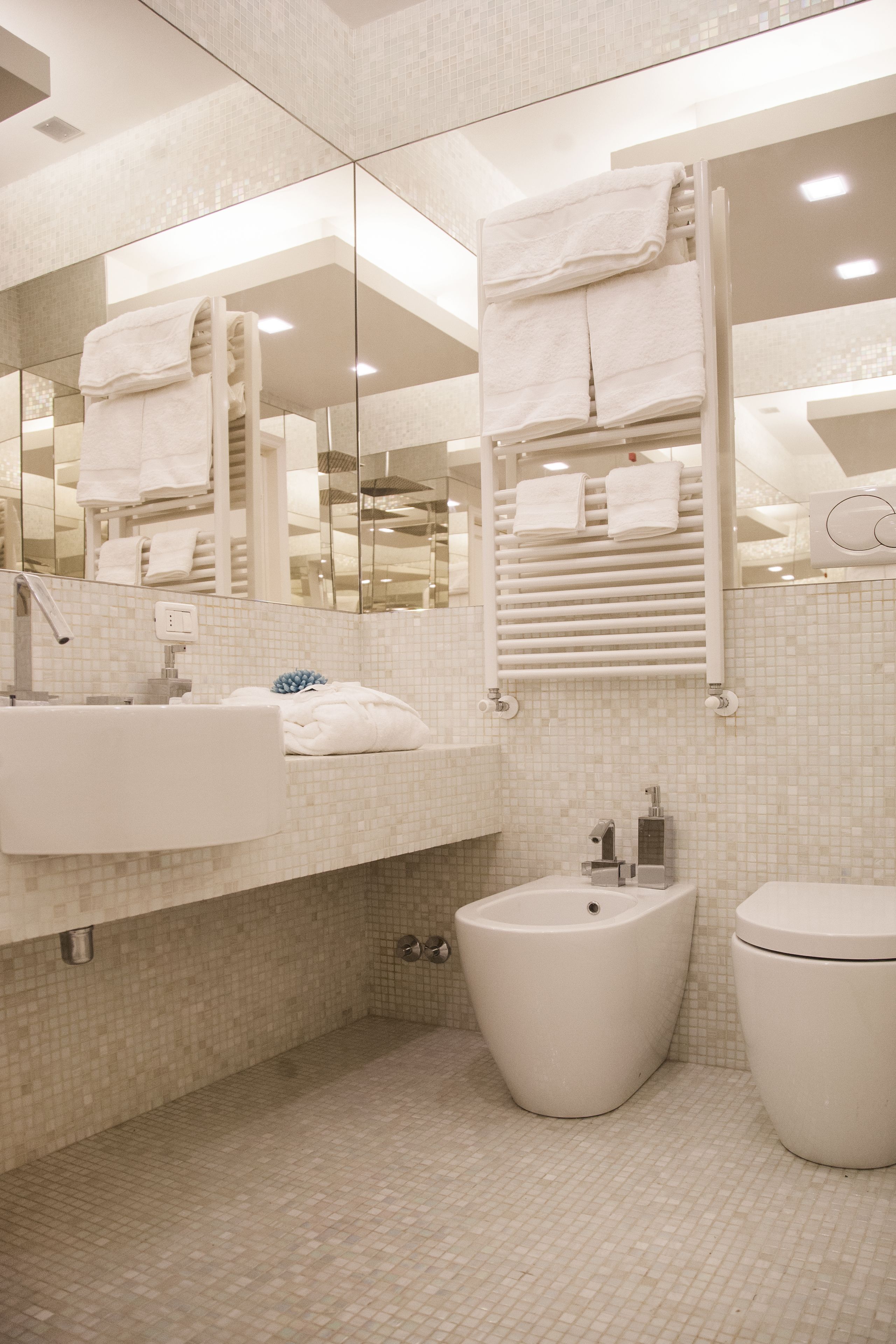 Un baño moderno con un espejo grande, un lavabo, un bidé y un inodoro.