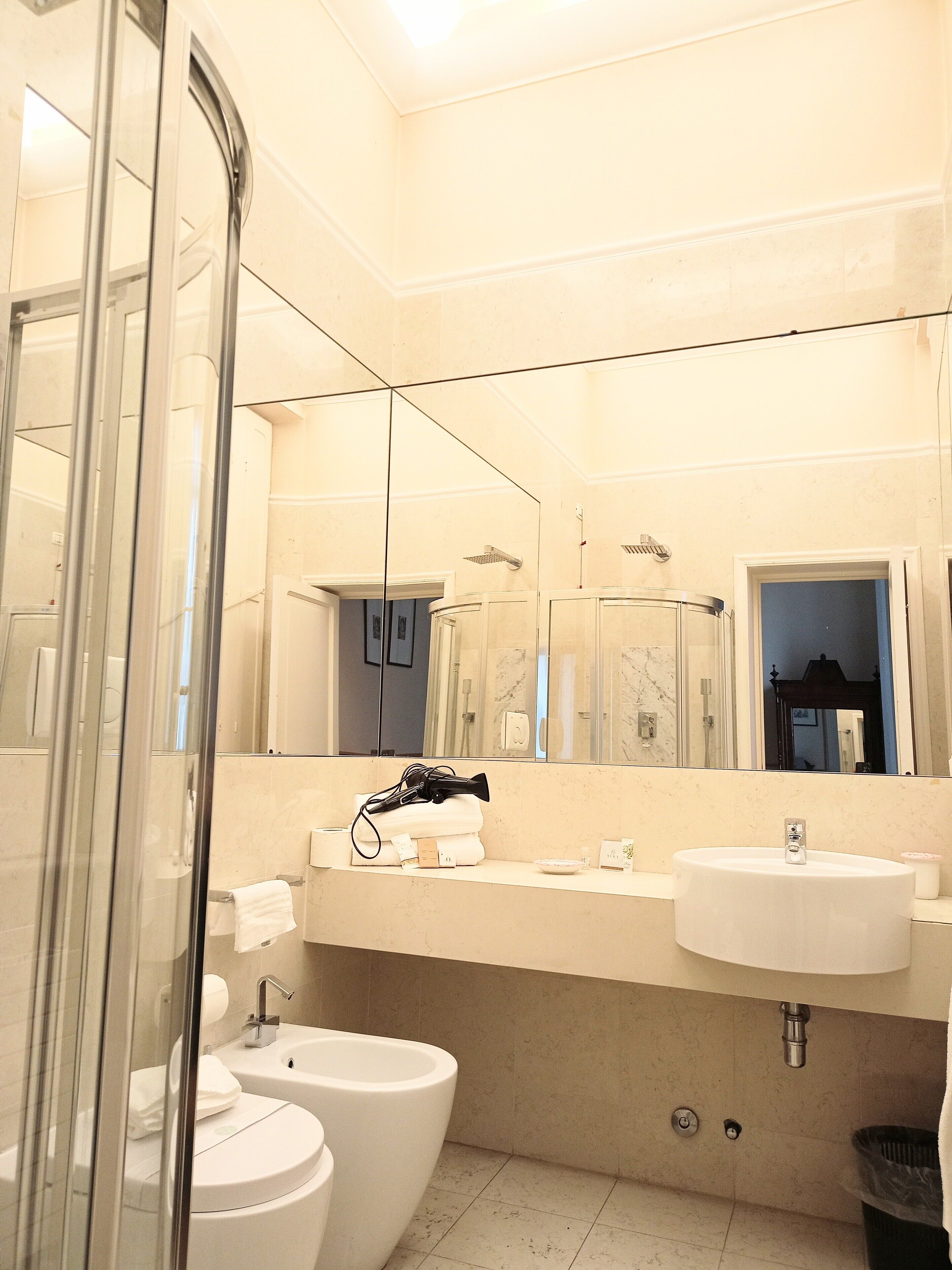Une salle de bain moderne avec une douche à parois de verre, deux lavabos et un grand miroir.