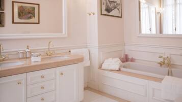 A bathroom with two sinks, a bathtub, and a large mirror.