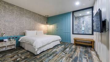 A bedroom with a bed, a wooden bench, a TV, and a patterned wall.