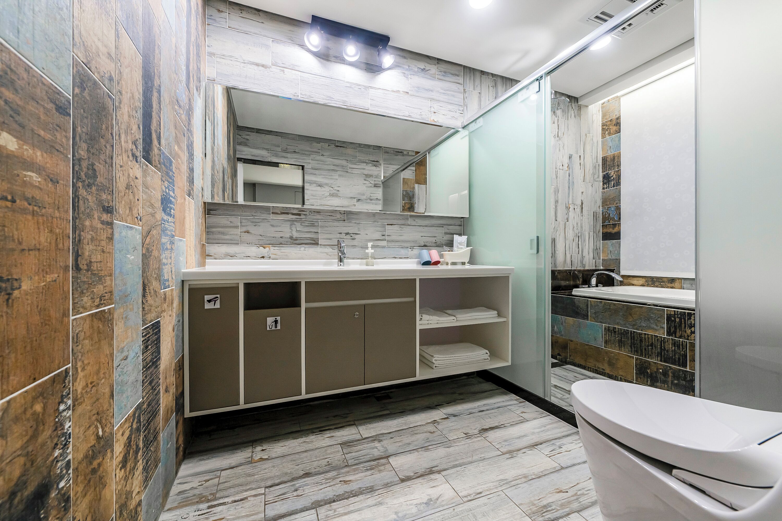 A modern bathroom with a marble floor, a large mirror, and a vanity with a sink and storage cabinets.