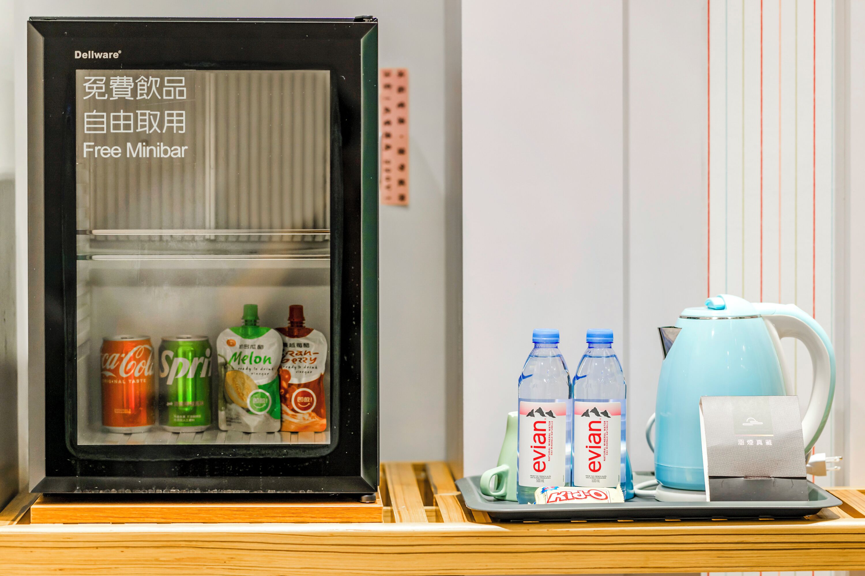 A mini-fridge stocked with beverages and a kettle on a tray.