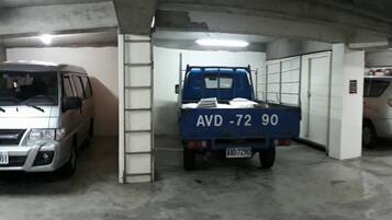 A parking garage with several vehicles, including a van and a truck, and a car in the background.