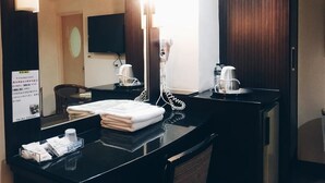 A hotel room with a black vanity, a hairdryer, a telephone, a coffee maker, and a neatly folded towel on the counter. - Hua Tai Hotel (Hsinchu)