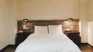 A hotel room with a large bed, two bedside tables, and a headboard with built-in lighting. - Hua Tai Hotel (Hsinchu)