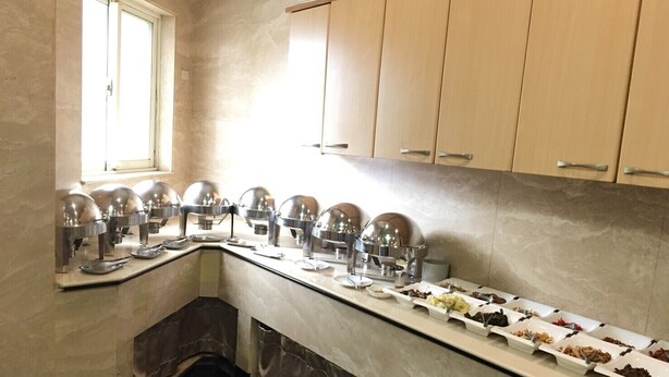 A buffet area with multiple food stations and a window with blinds. - Hua Tai Hotel (Hsinchu)