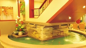 A circular water feature with a wooden structure, a staircase, and a potted plant. - TS Hotel - Scientex (Pasir Gudang)