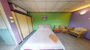 A hotel room with a bed, a chair, a nightstand, and a wall-mounted air conditioner. - TS Hotel - Scientex (Pasir Gudang)