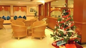 A lobby with wicker furniture, a Christmas tree, and a reception desk. - TS Hotel - Scientex (Pasir Gudang)