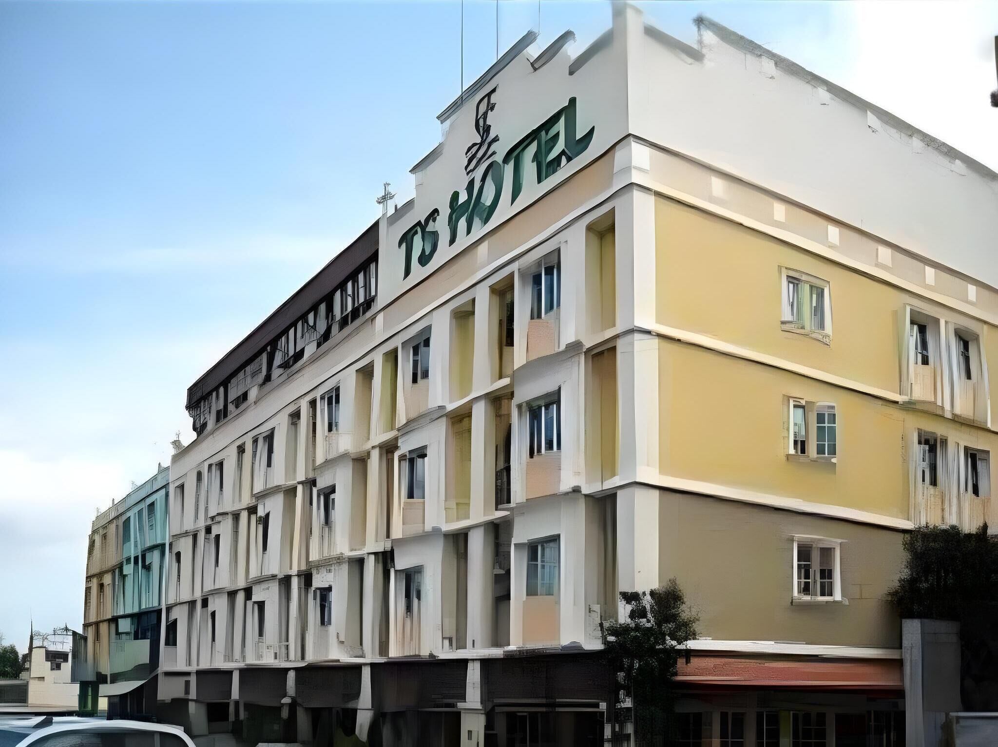 A multi-story hotel building with a sign reading "TS HOTEL".