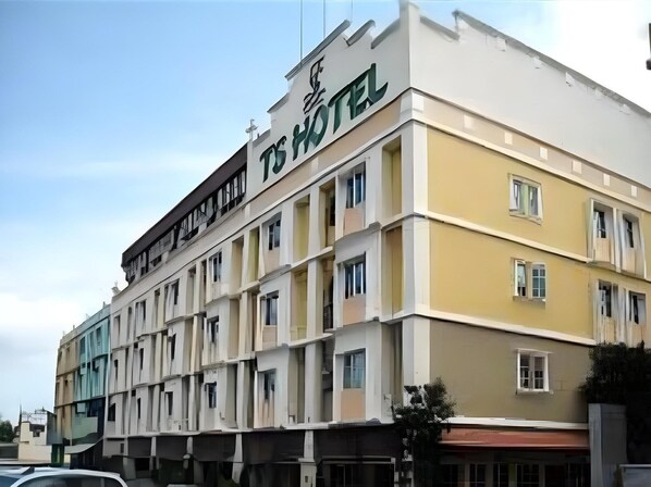 A multi-story hotel building with a sign reading "TS HOTEL".