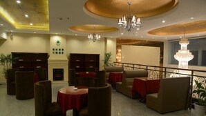 A hotel lobby with round tables, sofas, and a fireplace. - GreenTree Inn Huangshan Tunxi Old Street Hotel (Huangshan)