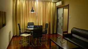 A room with a dining table, four chairs, a sofa, a hanging light fixture, and a sliding door. - GreenTree Inn Huangshan Tunxi Old Street Hotel (Huangshan)