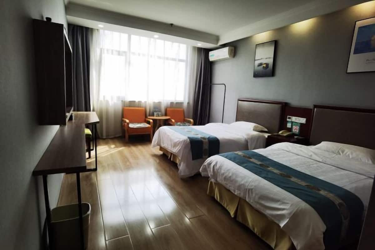 Een hotelkamer met twee bedden, een bureau, een stoel en een klein tafeltje.