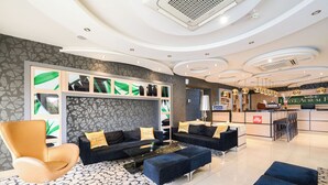 Um hall de hotel moderno com balcão de recepção, sofás e piso estampado.