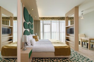 Una habitación de hotel con una cama grande, dos mesitas de noche, un escritorio y una silla.