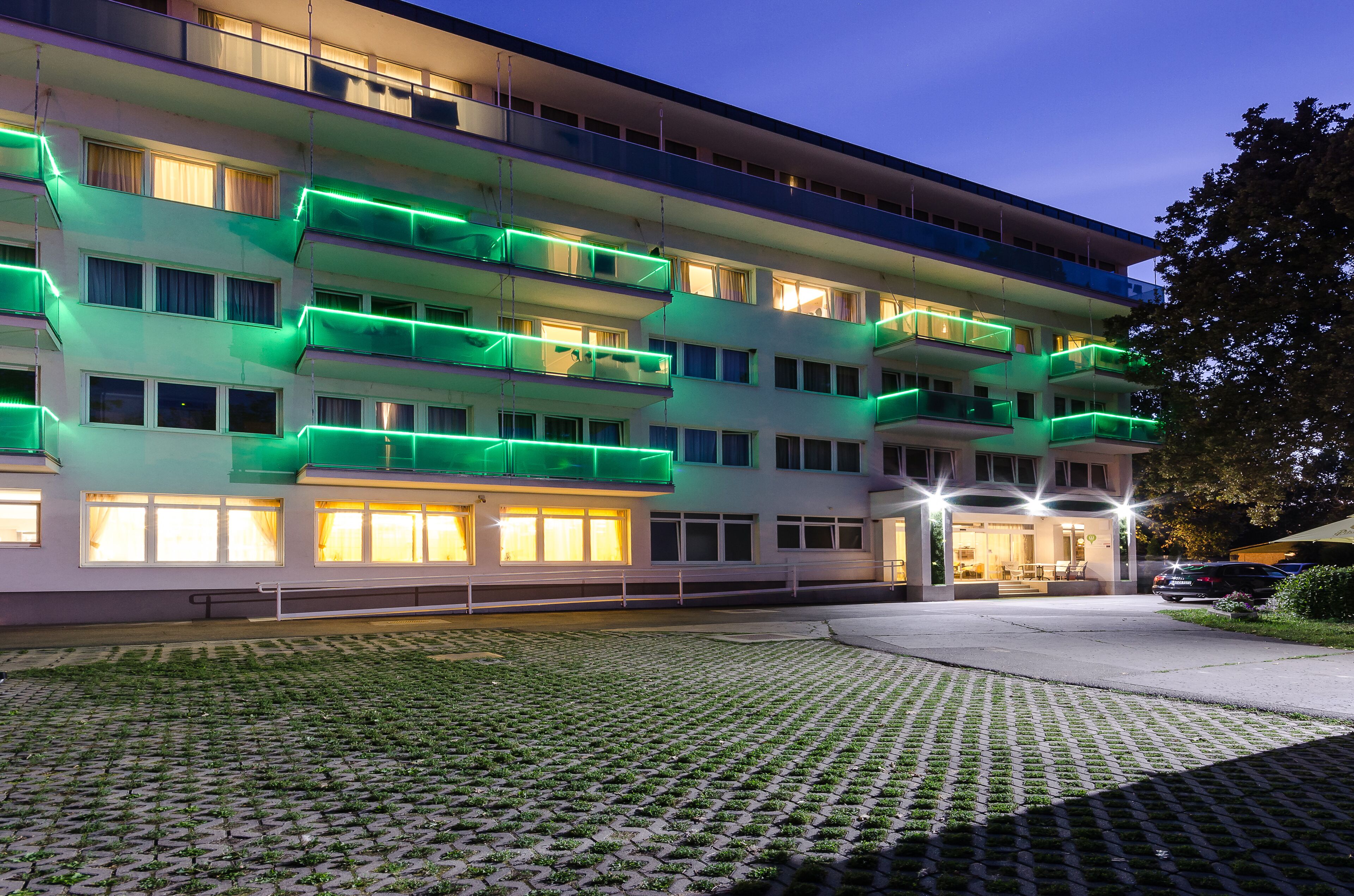 Un hotel de varios pisos con balcones, un patio empedrado y una entrada bien iluminada.