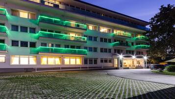 Un hotel de varios pisos con balcones, un patio empedrado y una entrada bien iluminada.