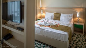 Quarto de hotel com cama, televisão, comando remoto e telefone.