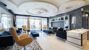 Um hall de hotel moderno com um sofá, poltronas, um balcão de recepção e um piso estampado.