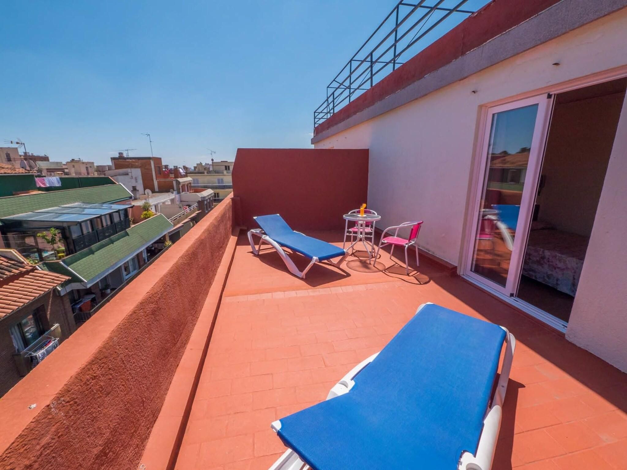 A balcony with two sun loungers, a small table, and a chair.