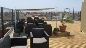 A rooftop terrace with outdoor seating, a potted plant, and a view of the cityscape. - Golden Sand (Lloret de Mar)