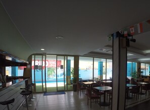 A restaurant with a view of the sea, indoor seating, and a bar area.