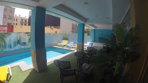 A pool area with artificial grass, lounge chairs, and a mural. - Golden Sand (Lloret de Mar)