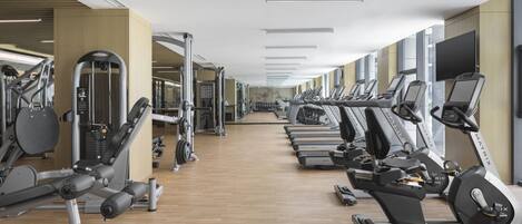 Une salle de sport équipée de tapis de course, de vélos elliptiques et d’appareils de musculation.