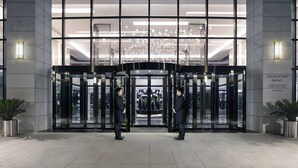 Een hotelentree met draaideuren, een kroonluchter en een bord met de tekst 'Courtyard Marriott'.