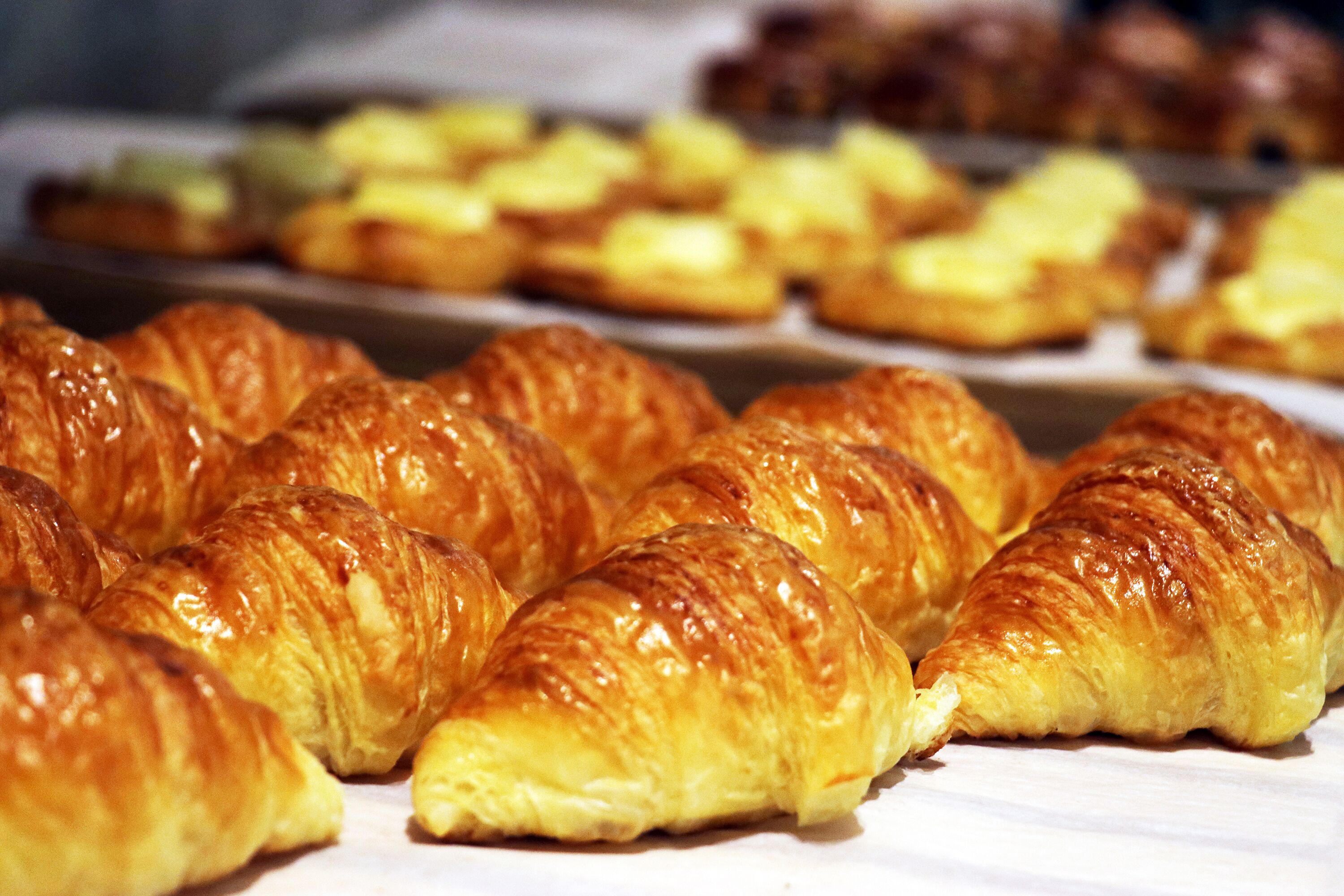 Een verscheidenheid aan gebak, waaronder croissants, is uitgestald.