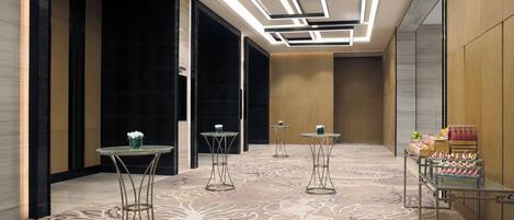 A hotel lobby with a patterned carpet, modern lighting, and a display of merchandise.