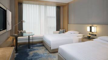 A hotel room with two beds, a desk, a TV, and a window with curtains.