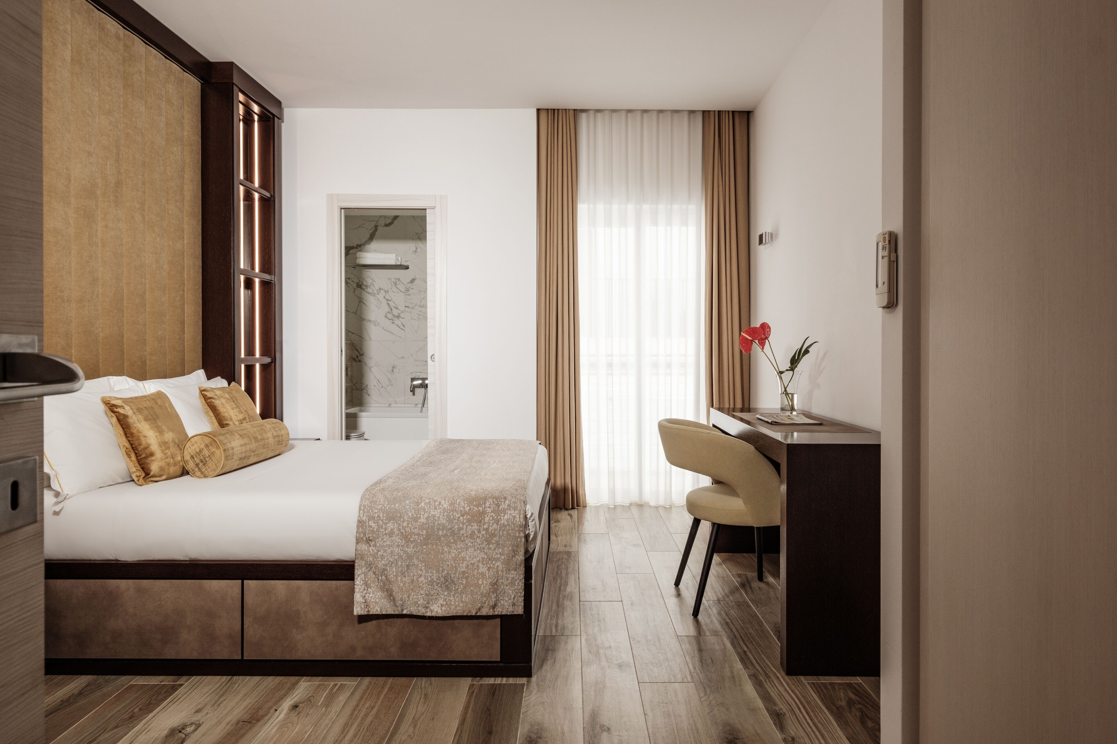 A modern hotel room with a large bed, a desk, and a shower area.