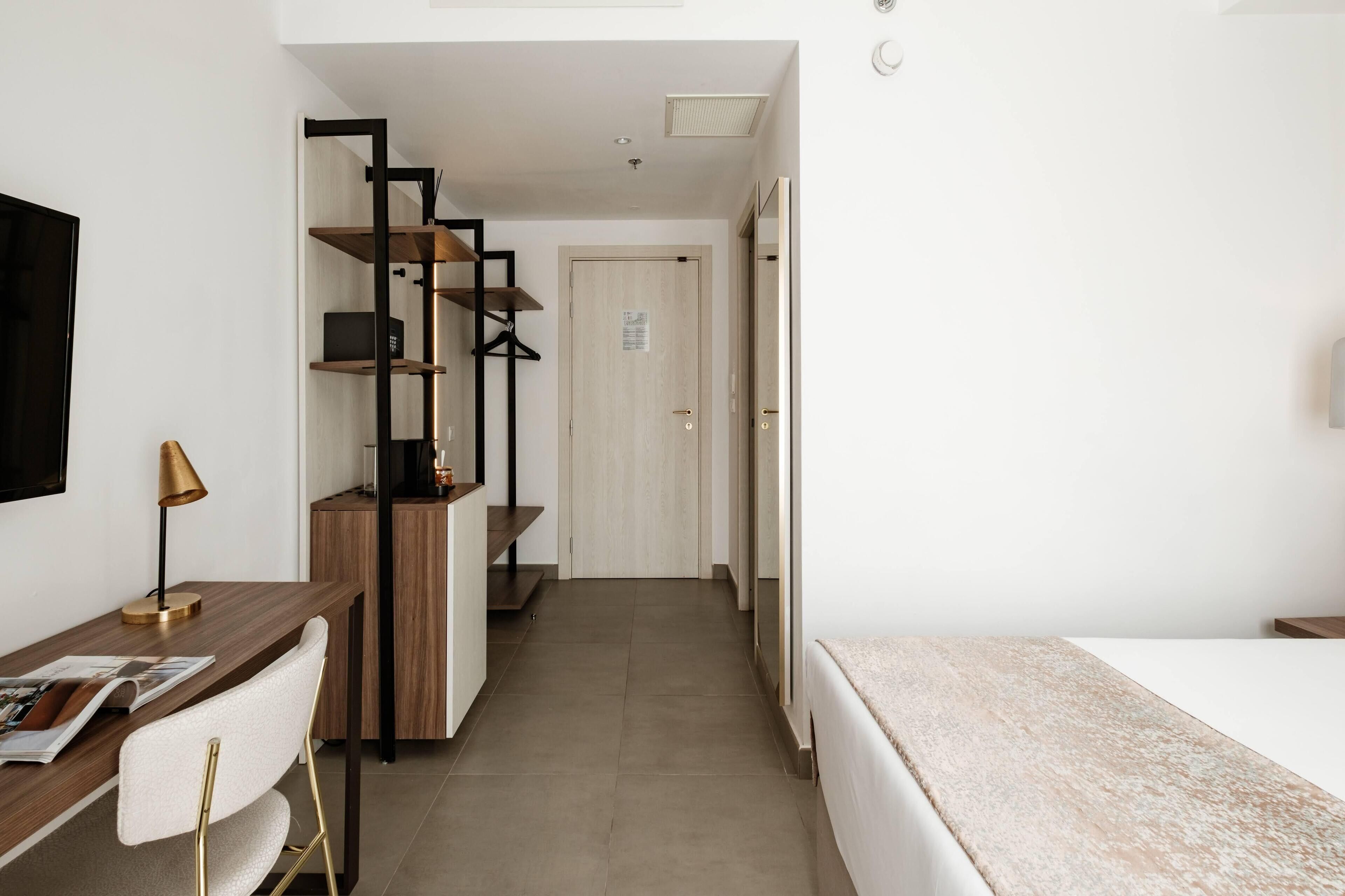 Una habitación de hotel moderna con un escritorio de madera, una silla, una cama y una escalera que conduce a una puerta.