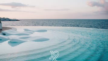 Relax by the serene infinity pool overlooking the sea, surrounded by a well-maintained area with a clean design.