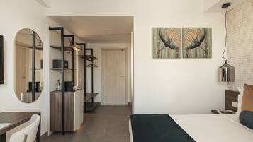 Un dormitorio moderno con cama, escritorio y espejo. Se ve una puerta que conduce a otra habitación.