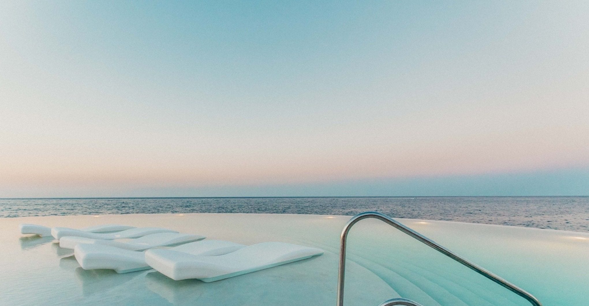 A poolside area with lounge chairs and a view of the sea.