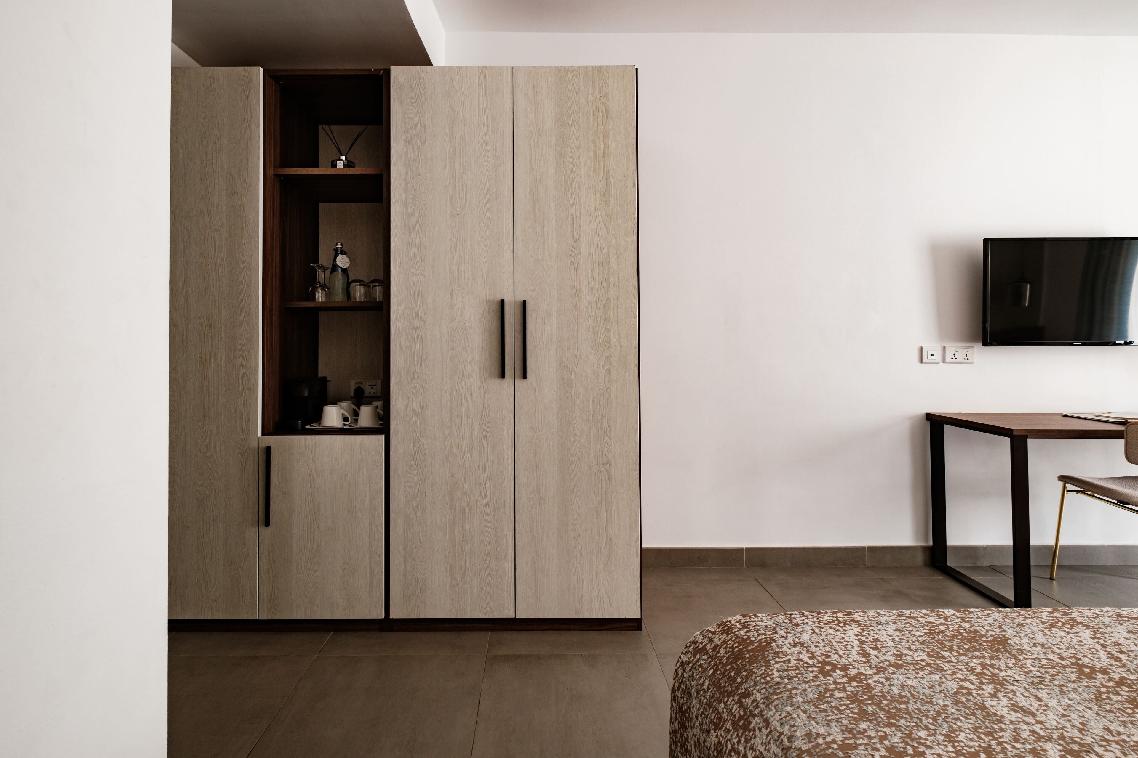 A modern bedroom with a wardrobe, a bed, a TV, and a small table.