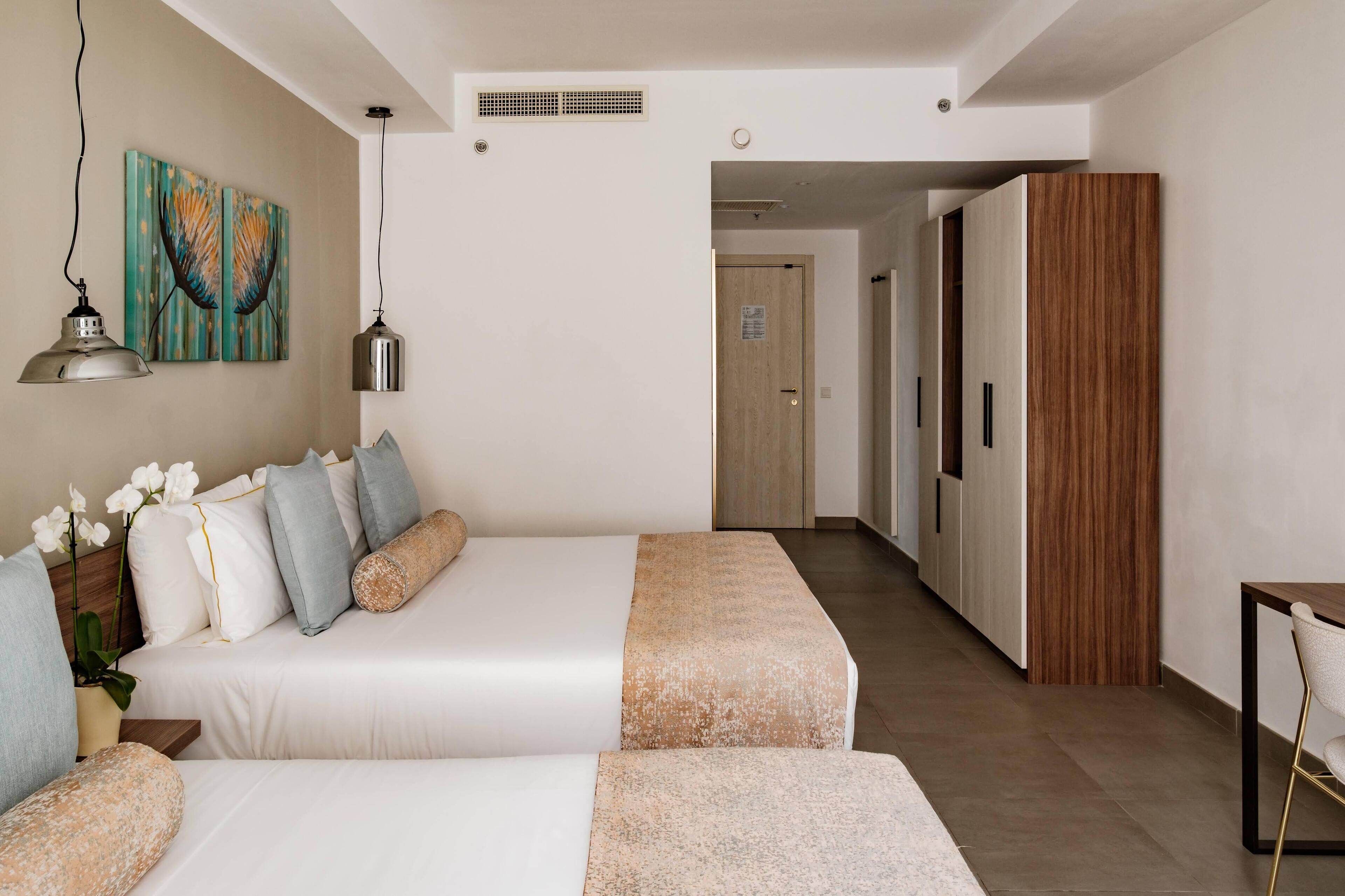 A modern hotel room with a large bed, a wooden wardrobe, and a small table with a chair.